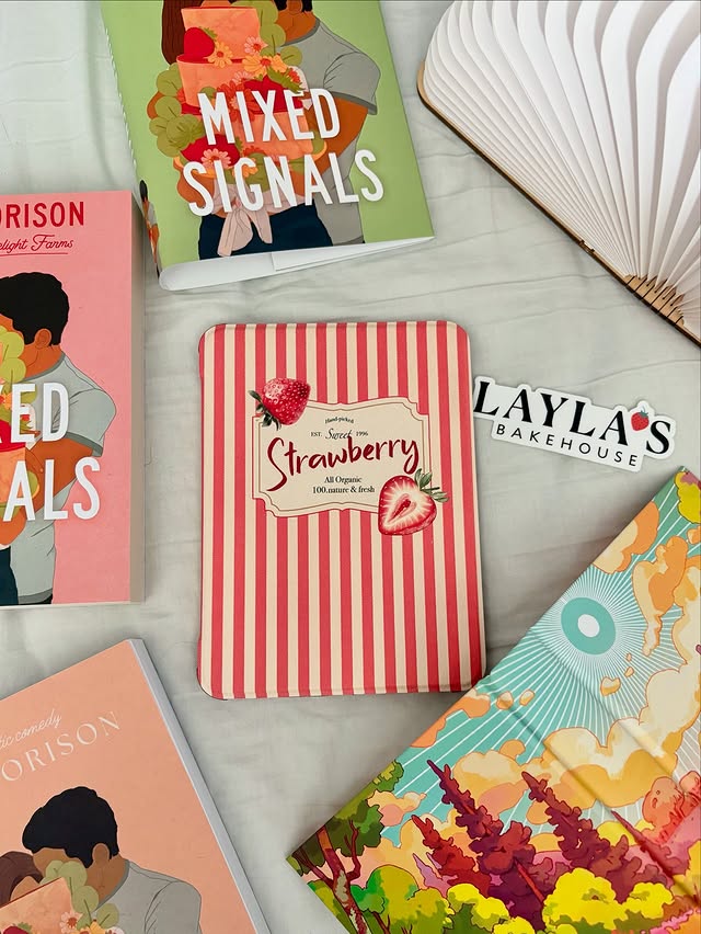 Collection of books and a notebook with visible titles and designs on a light surface.